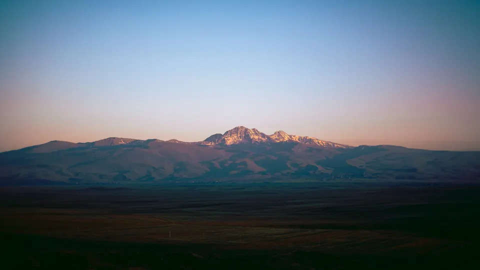 Mount Aragats glowing pink at sunset above the plateau