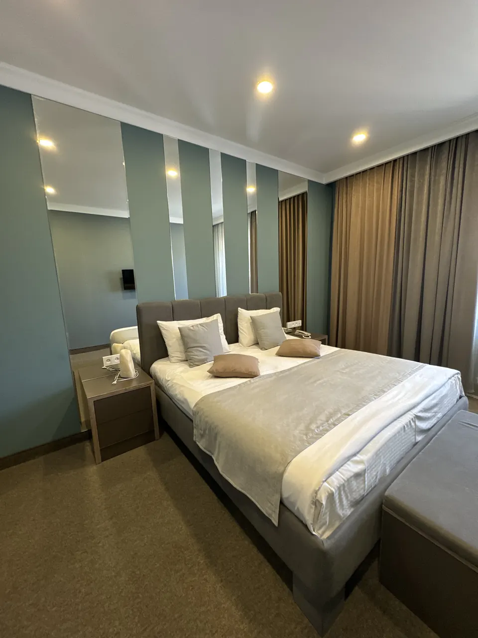 Suite bedroom with grey upholstered headboard and panelled wall